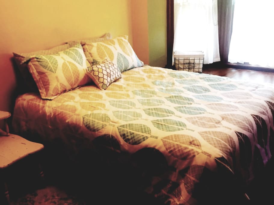 Queen bed in room with bay window and quaint window seat. This room also has a small workspace desk.