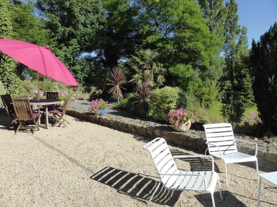 Grande terrasse ensoleillée avec table et salon de jardin