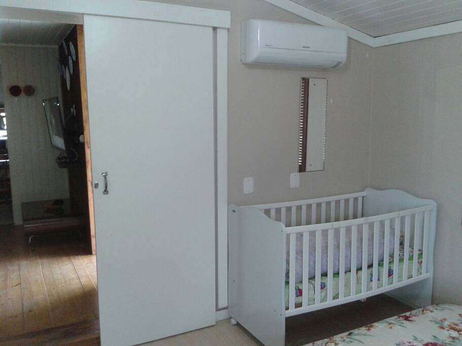 Quarto maior climatizado com ar condicionado contendo cama de casal, uma cama de solteiro, um berço, um roupeiro duas portas.