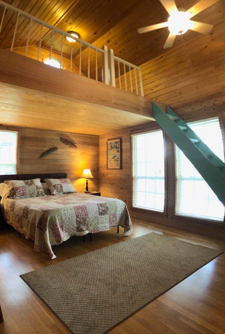 Bedroom features a queen size bed with double windows overlooking the river. There is a loft above.