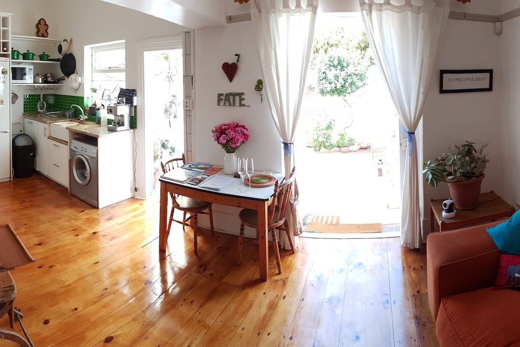 Open plan sitting area and kitchen with doors opening onto small back yard.