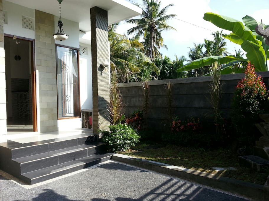 Clean, Modern touch of entrance with small garden and big carport for car and bikes.