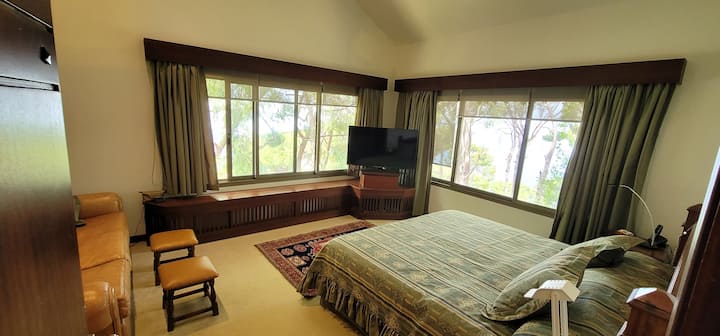 Dormitorio principal de la planta superior con sofá y vistas al bosque