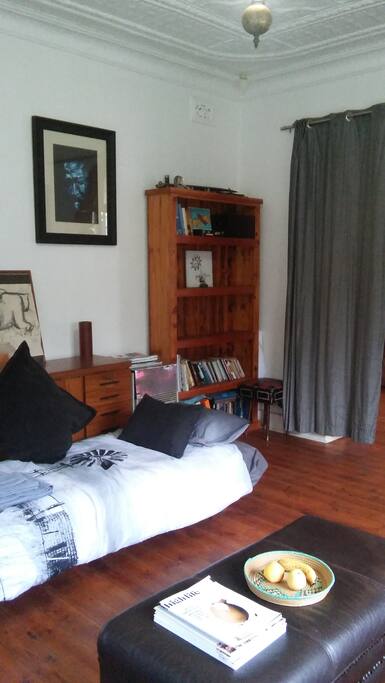 The single sofa bed with bedlinen and towels next to the shelves where guests can store some of their clothes and books