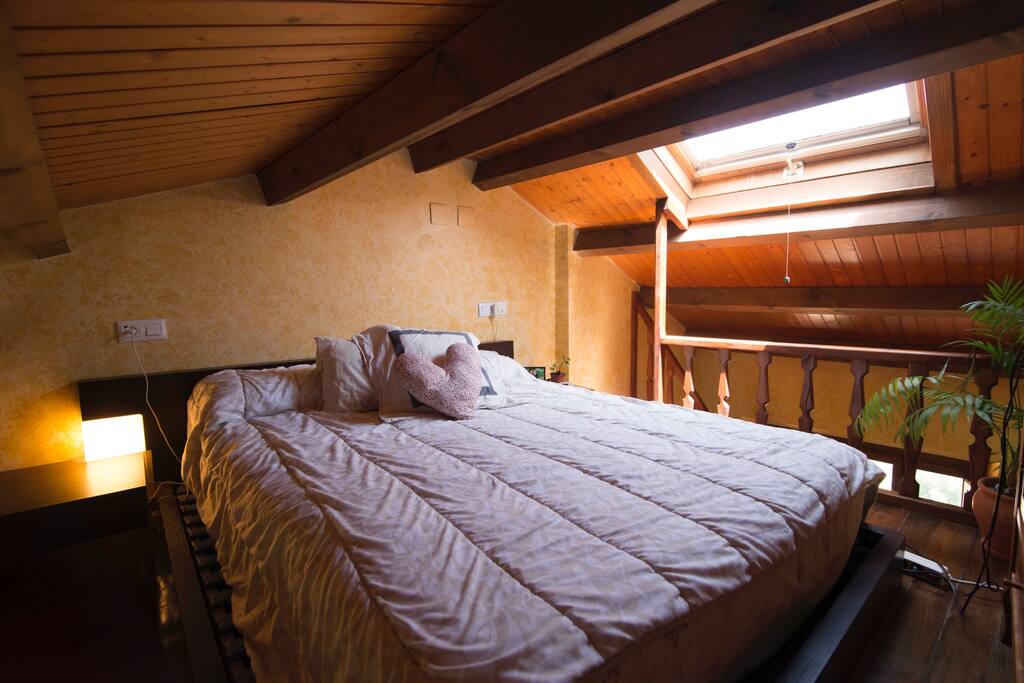 Altillo con techos de madera y ventana con vistas al cielo. Cama de matrimonio de 150x200