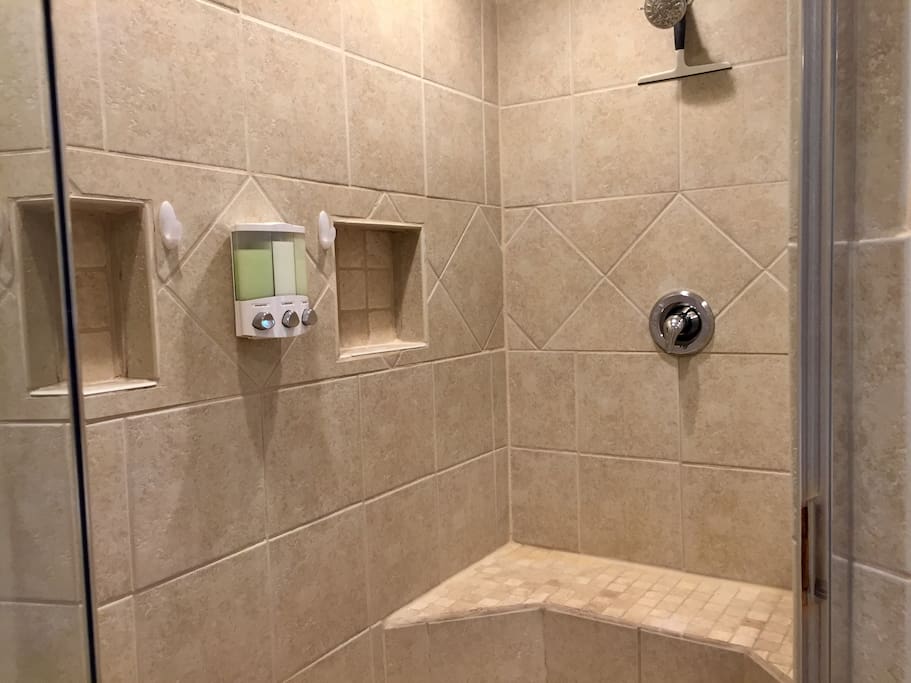 Spacious tiled walk-in shower with dispensed eco friendly bath products