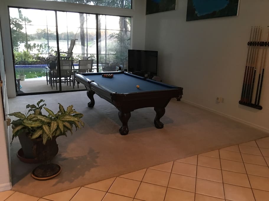 Billiard room from front door, looking out to covered lanai, pool and lake in background.
.