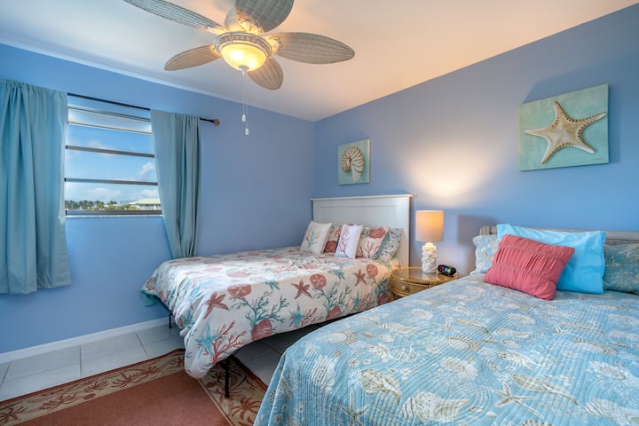 Guest room with queen and twin bed and large dresser.  Water views out the guest bedroom.