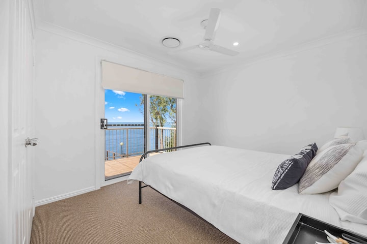 ห้องควีนไซส์หลังที่สองที่มีตู้เสื้อผ้าบิวท์อินเครื่องปรับอากาศและประตูออกไปยังระเบียงพร้อมพื้นที่นั่งเล่นที่อบอุ่น