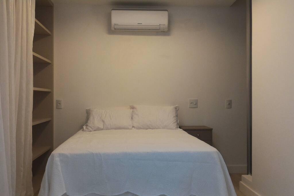 Cama casal com criado mudo e estante, ar condicionado