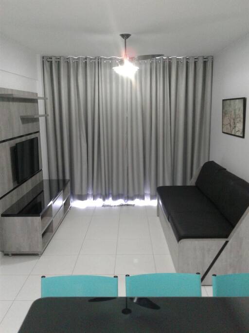 Sala com tv, ventilador de teto, sofá bicama.