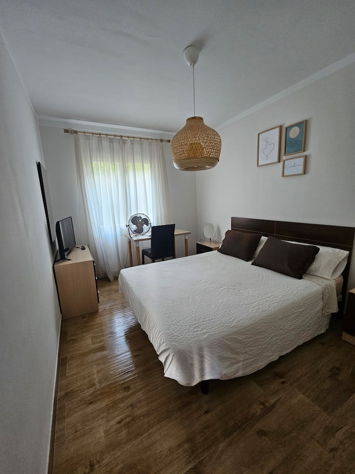 חדר שינה זוגי עם ארון מובנה, שולחן עבודה וטלוויזיה חכמה. נוף לגינה.