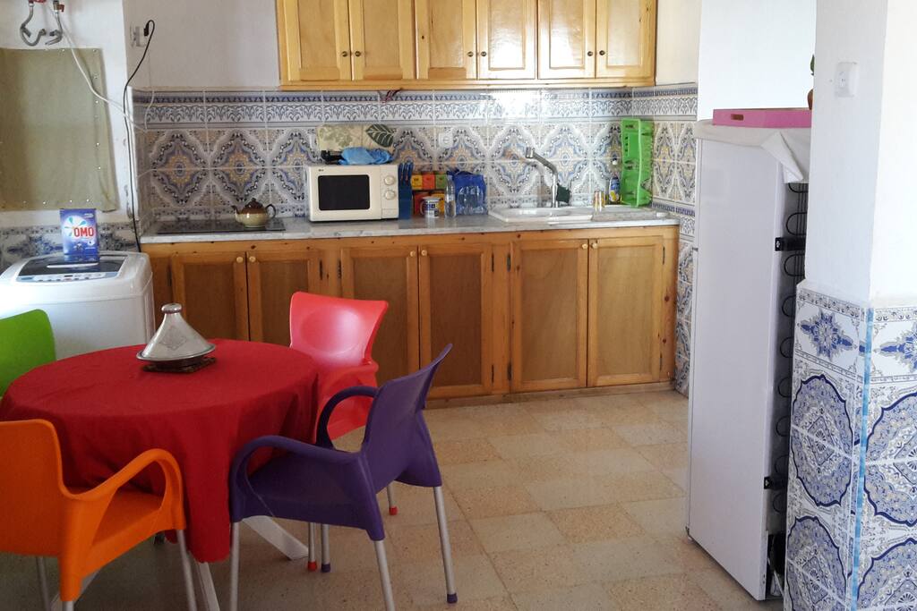 Cuisine entièrement ouverte et éclairée.
La cuisine est ouverte sur le salon et est équipée avec : réfrigérateur/congélateur, mini-four, micro-ondes, cafetière, bouilloire, grille-pain, couscoussier, poêles, casseroles, ustensiles cuisine, vaisselles, couverts, table, chaises, placards, machine à laver, coffre-fort...