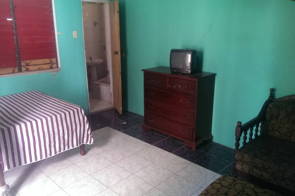 a large room with furniture and bathroom entrance.