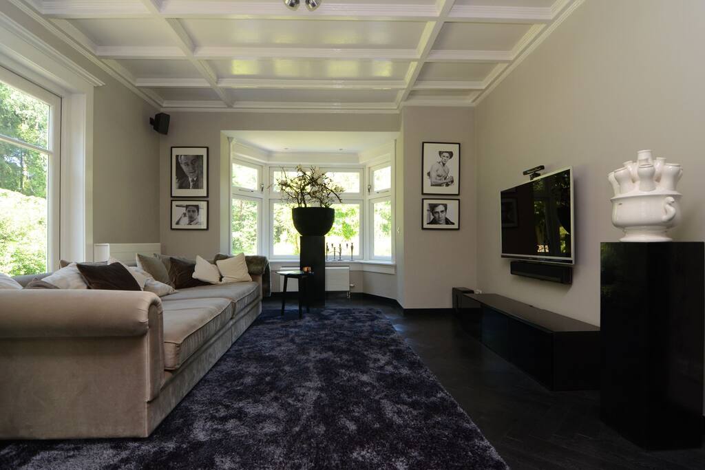 De televisiekamer heeft een heel grote bank, Sonos 5.1 surround-system en Sony Playstation