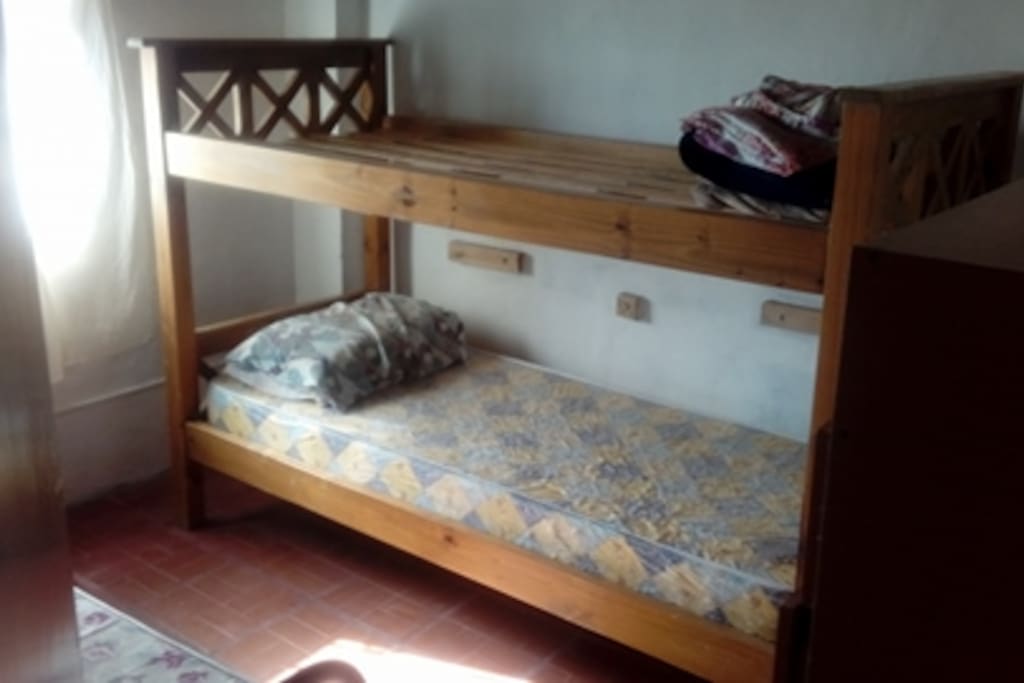 Dormitorio con tres camas simples y vista al mar