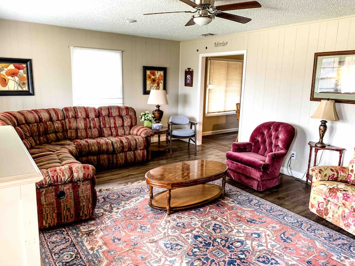 Beautiful living area with a huge Persian rug, sectional with reclining ends, two recliners, wood end tables, coffee table, and entry table. Also equipped with a 32-inch tv.
