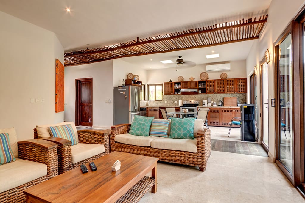 Open living room and kitchen area allowing for guests to enjoy their time together. Natural stone floors throughout.