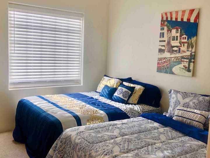 Primer dormitorio con camas dobles tamaño queen y televisión inteligente, portaequipajes y espacio en el armario. Capacidad para dos a cuatro adultos.