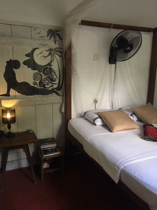 Tha main bedroom with mosquito net, fan and reading lamp.