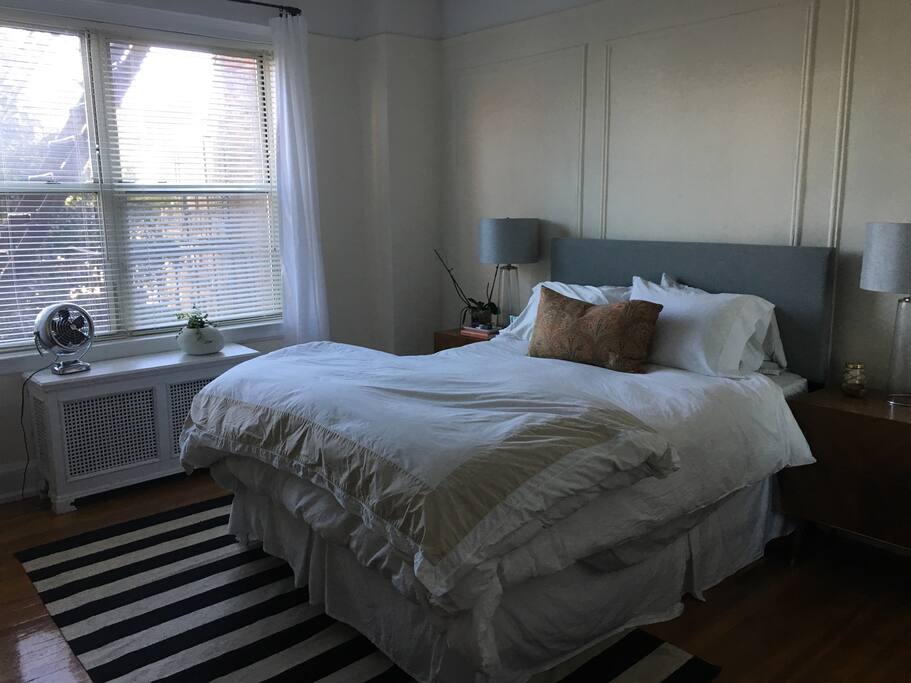 Comfortable queen size bed with down bedding in a bright and spacious bedroom.