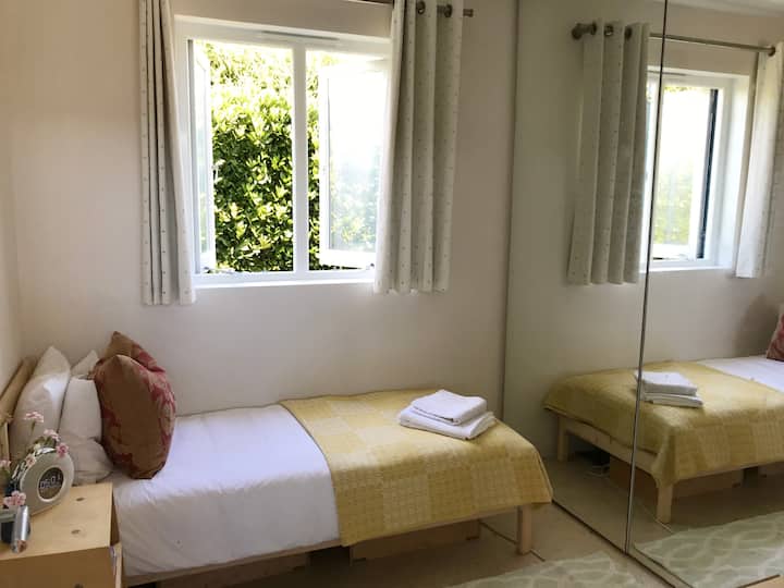 Втора спална соба со единечен кревет, големи огледала, биро и доволно простор за гардероба