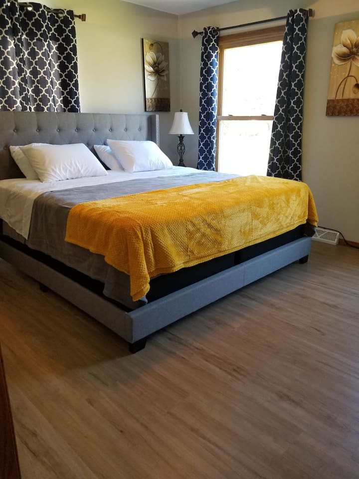 Основна спалня. Основен етаж. Голямо двойно легло, скрин, килер, нощни шкафчета, смарт телевизор, вентилатор на тавана и вентилатор за кутии.