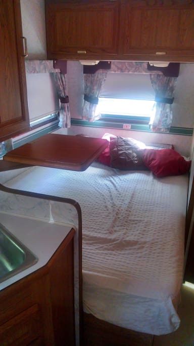 Full size bed, with pillows, sheets and a table to hold your phone, and bedside accessories.