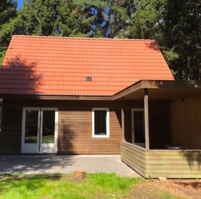 Het vakantiehuis in het voorjaar met veranda en picknickbank (er zijn ook tuinstoelen aanwezig)