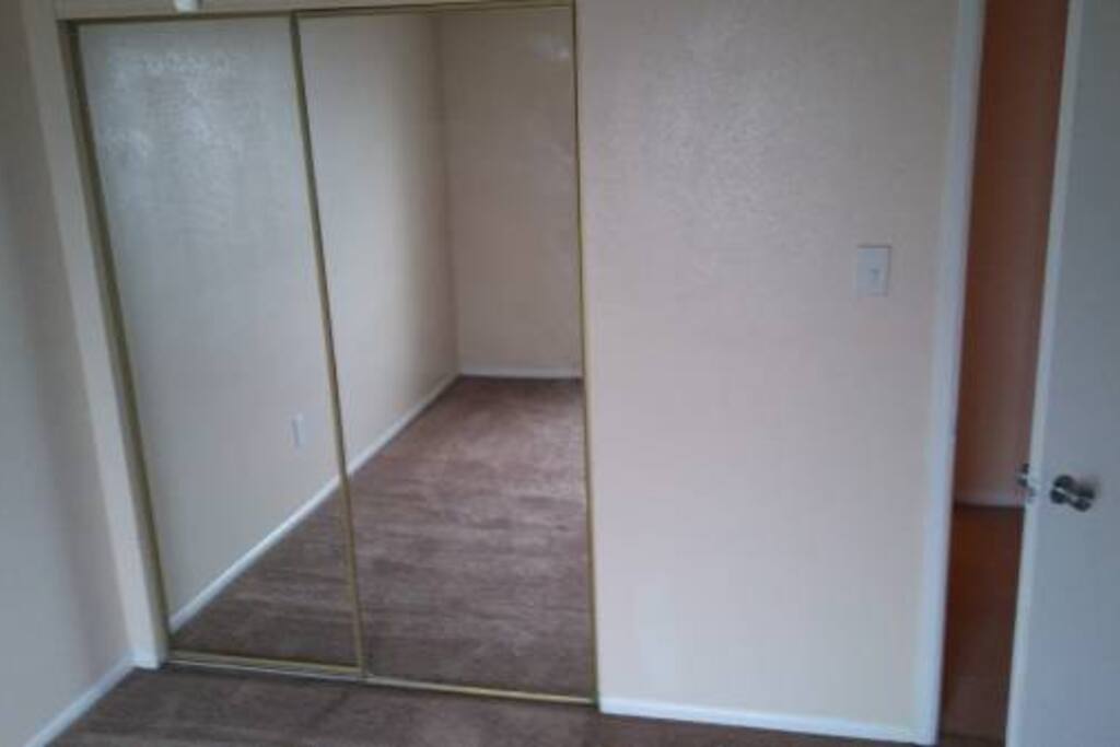 Two sliding full mirror closet doors, clean, tan carpet.