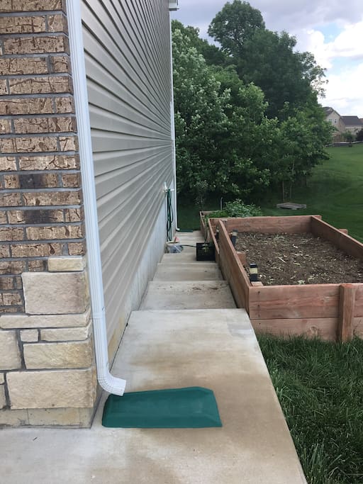 Slopping garden and stairs leading to apartment entrance.