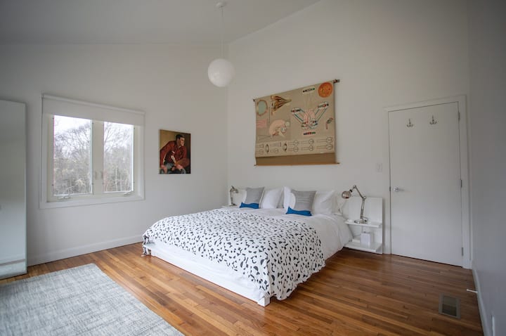 Master bedroom with vaulted ceiling, King bed, and windows overlooking trees.
