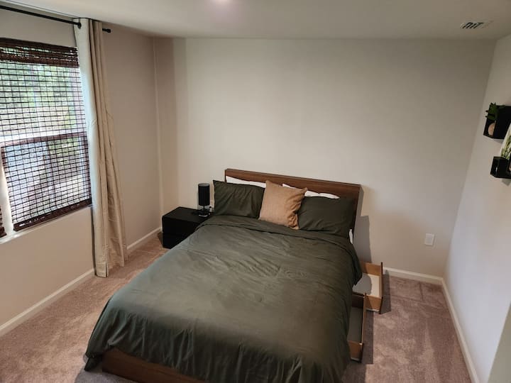 غرفة النوم الرئيسية مجهزة بمصباح قابل للتعديل وأدراج تخزين تحت السرير بحجم كوين.