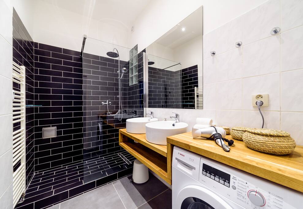 Spacious bathroom with a comfortable rain shower, two bathroom sinks, drying rail and washing machine at your service.