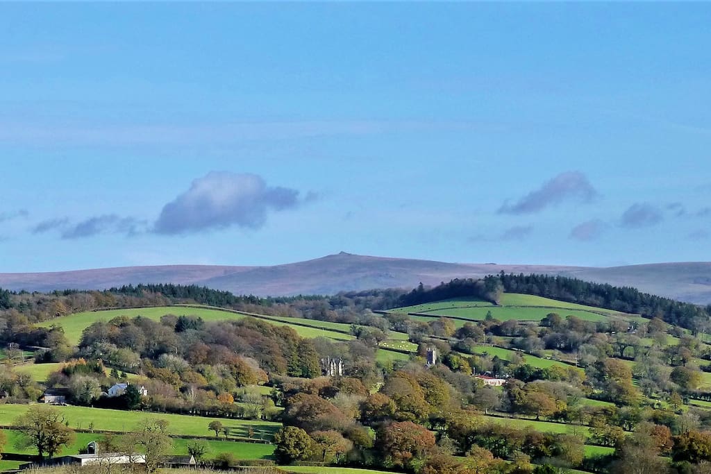 The house in its landscape: The house is at front centre, to the left of the church. Dartmoor behind.