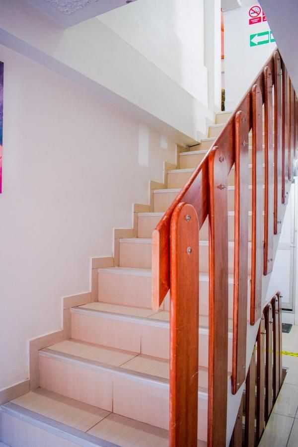 A staircase lined with wooden railing ascends to the upper floor, featuring light-colored tiles that enhance brightness. The walls are painted in a neutral tone, and a colorful artwork is visible to the left, adding a touch of character to the space.