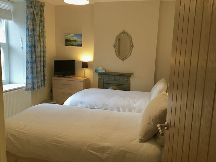 Acogedoras camas individuales en el dormitorio dos con jardín y vistas de largo alcance al macizo de Skiddaw.