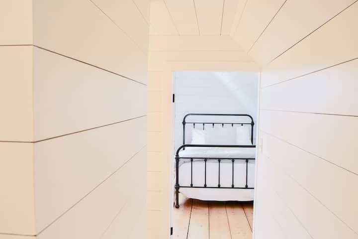 Shiplap hallway looking into the upstairs bedroom, which offers 2 double guest beds.