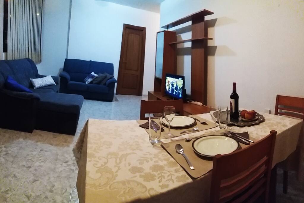 Salón comedor perfectamente iluminado y ventilado con 2 sofá, televisor, comedor de 4 puestos