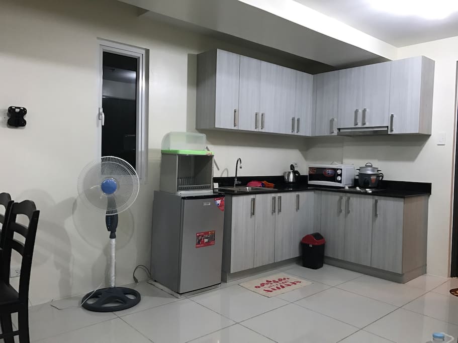 Kitchen w/ refrigerator, microwave, kettle, rice cooker, cooking range, and kitchen utensils