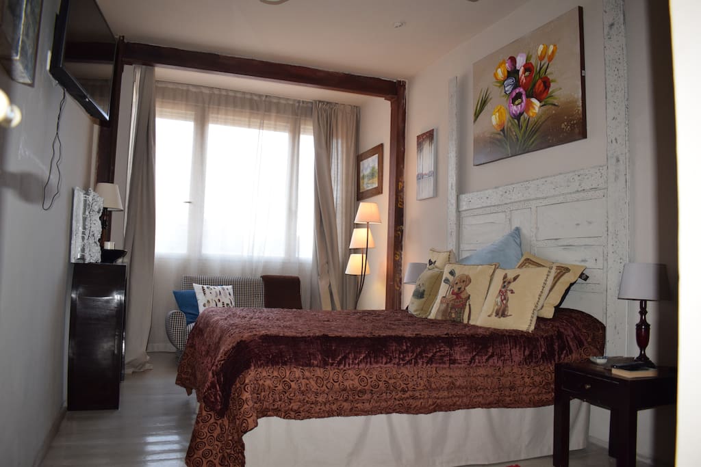 Habitacion con cama de matrimonio, pequeño sofa y armario empotrado.