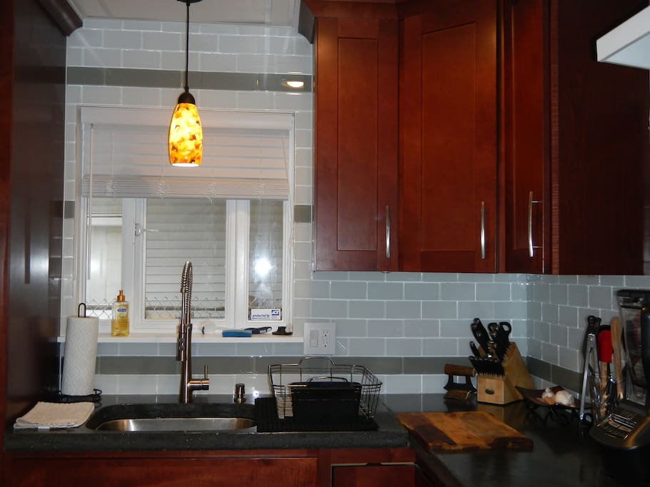 Concrete counter, undercabinet lights, stainless steel sink and sharp cuttlery make prepping any meal a treat
