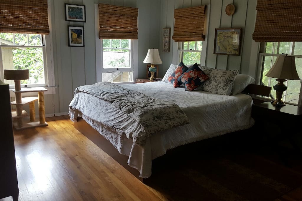 large bright bedroom with hardwood floors connects to porch and kitchen area