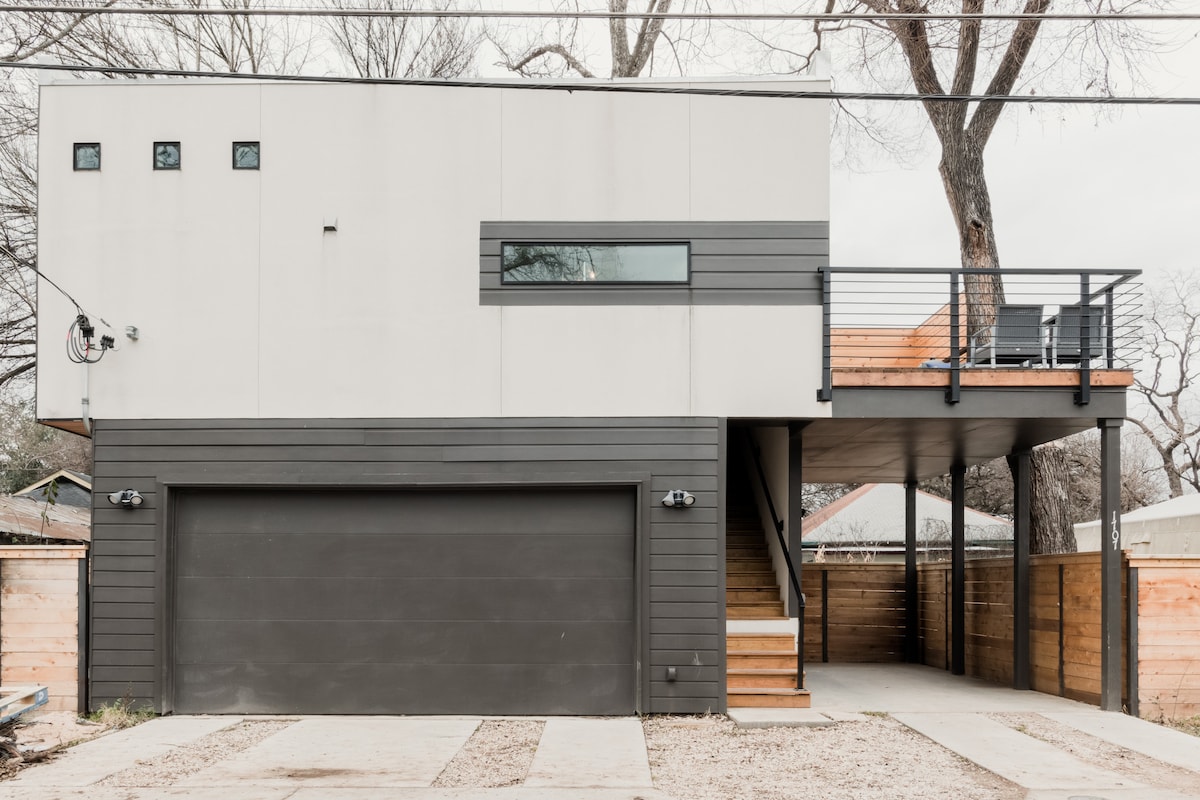 The modern exterior of the two-story detached apartment features a sleek design with a combination of light and dark materials. A private deck is accessible from the upper level, complemented by large windows that allow natural light into the space.