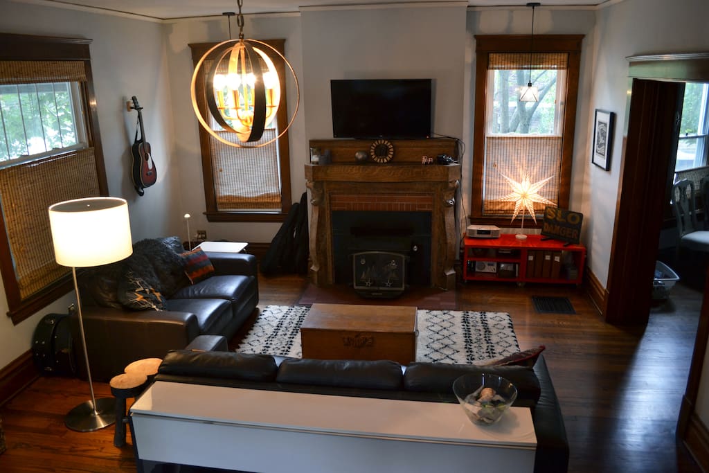 Large, open living room with leather couches, Morrocan shag rug, flat-screen TV, art/antiques, and good lighting