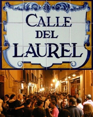 A vibrant street sign reading 'Calle del Laurel' is displayed prominently. Below, a bustling scene of people enjoying the lively atmosphere in the evening is captured, showcasing an active area lined with restaurants and bars, enhanced by warm street lighting.