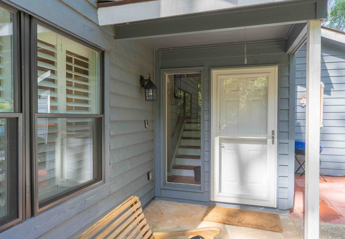 An inviting entrance is showcased, featuring a front door flanked by large windows. Natural light filters through the windows, illuminating the space. A wooden bench is positioned on the porch, offering a resting place before entering the home.