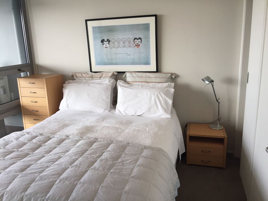 Your bedroom with queen bed , wardrobe, dressing gowns, suitcase stands and doors open onto deck