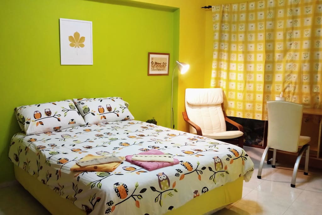 Private room with shared bathroom, queen sized bed, reading chair, work table and wardrobe