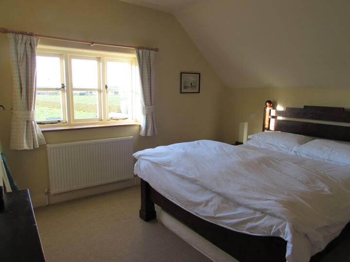 Spálňa 1, manželská posteľ veľkosti King, vlastná kúpeľňa a krásny výhľad na zadnú záhradu a polia za ním.